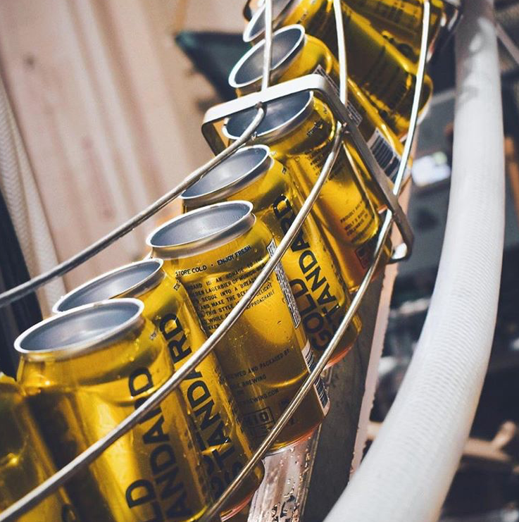 Beer cans with a shrink sleeve can wrap going through a filling line.