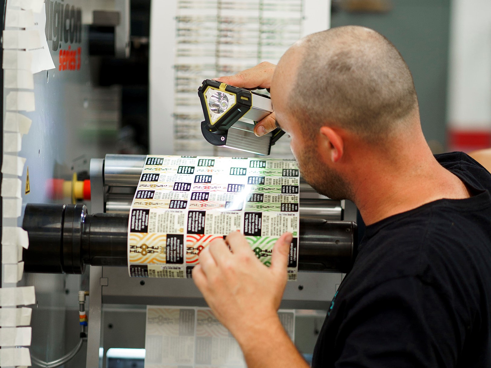 A man examining printed labels for defects.