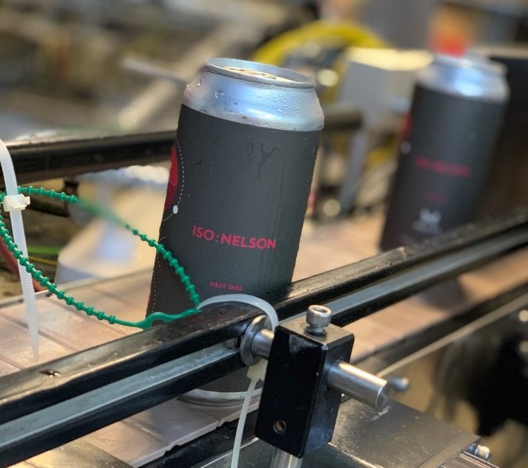 A cold, wet beer can with a pressure sensitive label going through a filling machine.