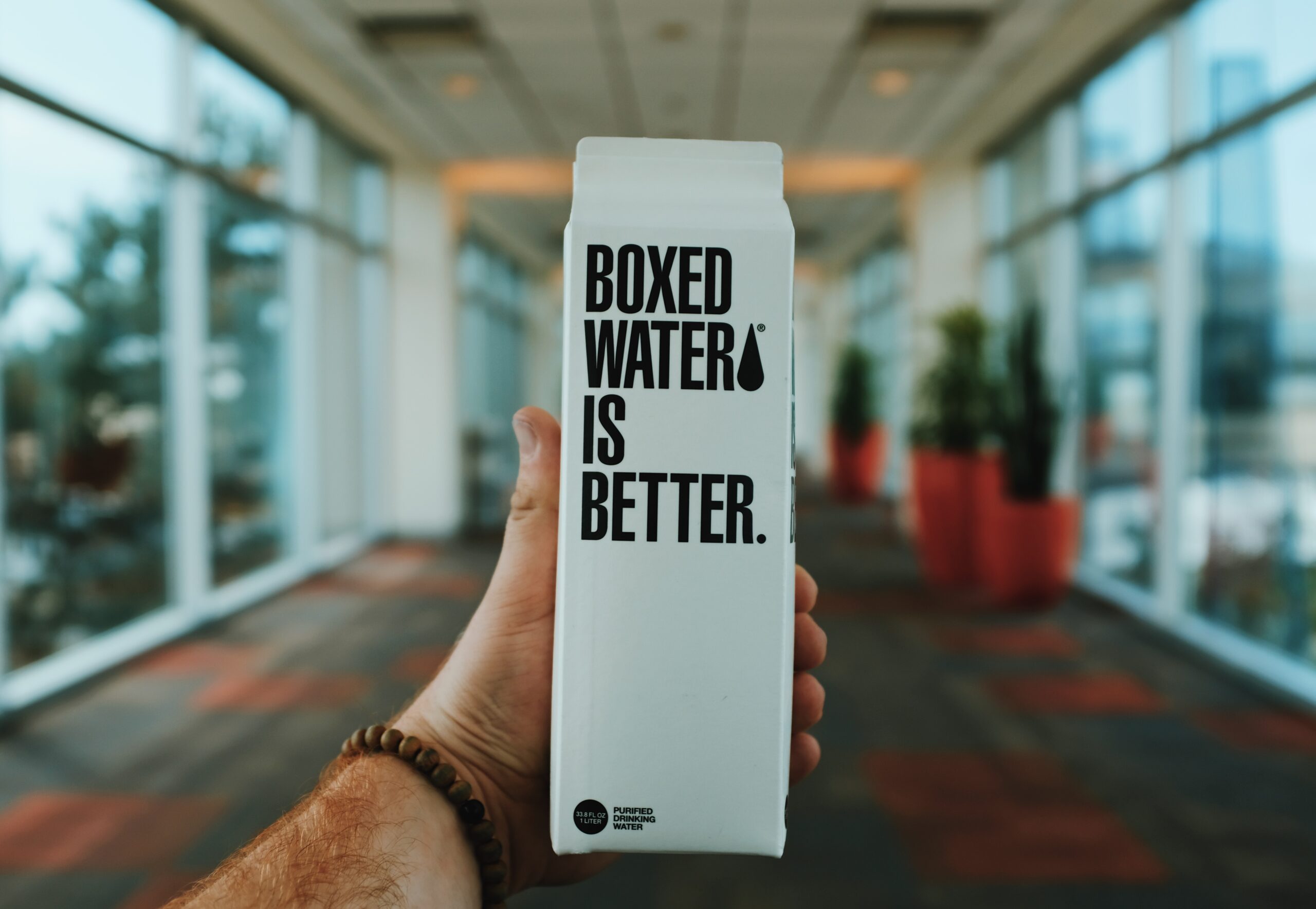 A hand holds Boxed Water, showing a bold statement on the label.